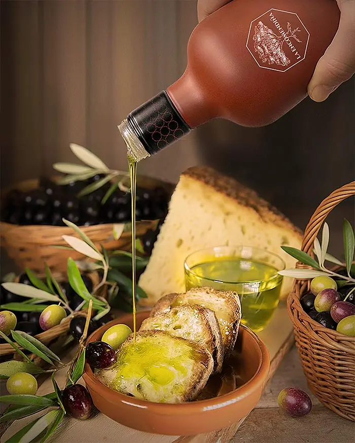 bodegón de alimentos con pan y aceite de oliva cayendo sobre el mismo.